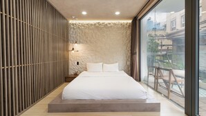 Una camera da letto moderna con un ampio letto, vista sull'esterno e una parete dalla texture particolare.