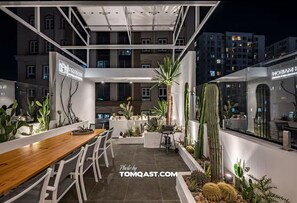 Un giardino interno moderno con un tavolo e sedie di legno, circondato da diverse piante grasse e vegetazione.