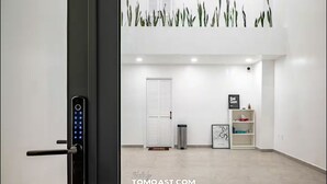 Een modern interieur met een digitaal slot op een deur, een witte deur, een prullenbak, een lijst met een afbeelding en een plank met spullen.