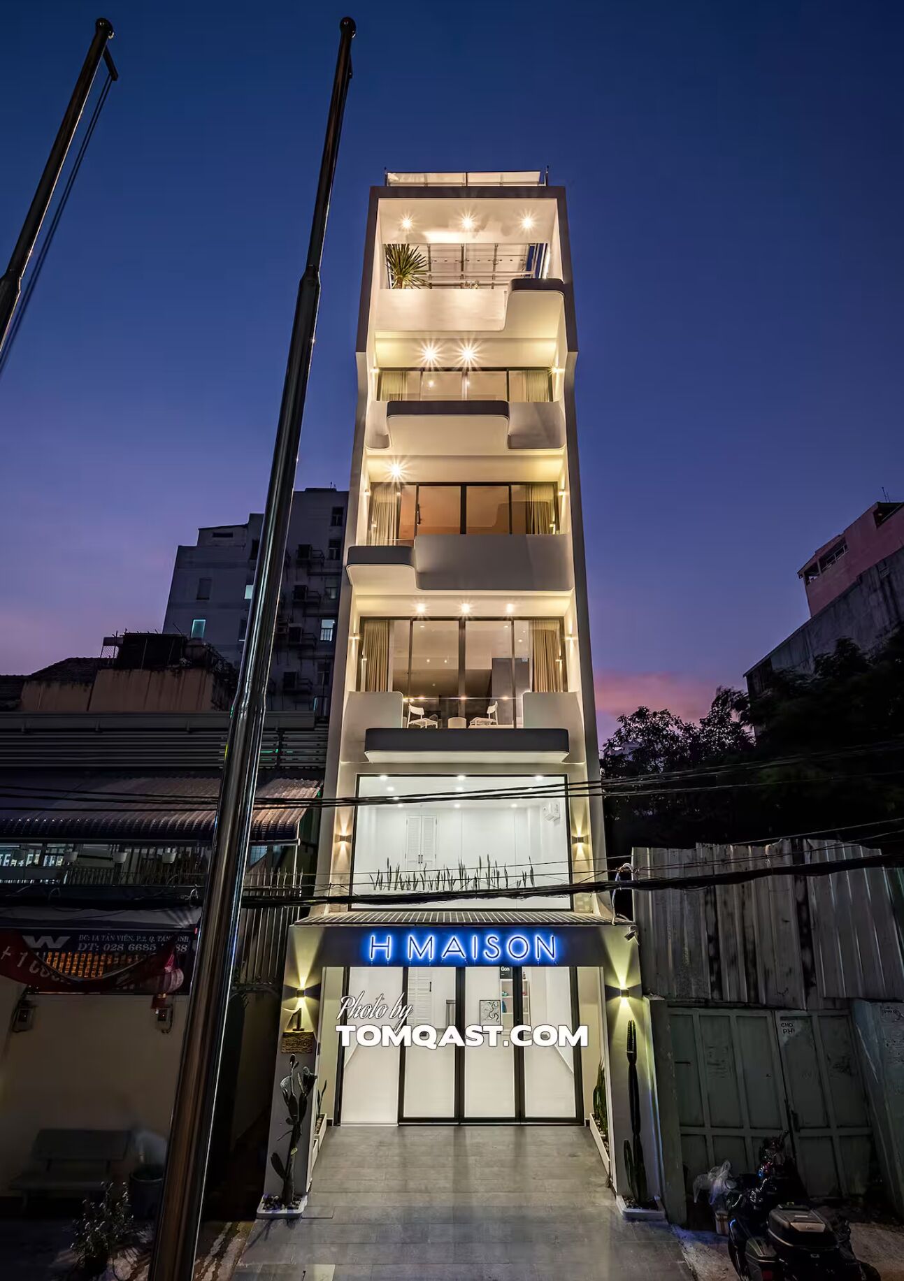 A modern multi-story building with a well-lit entrance and a sign reading "H MAISON".