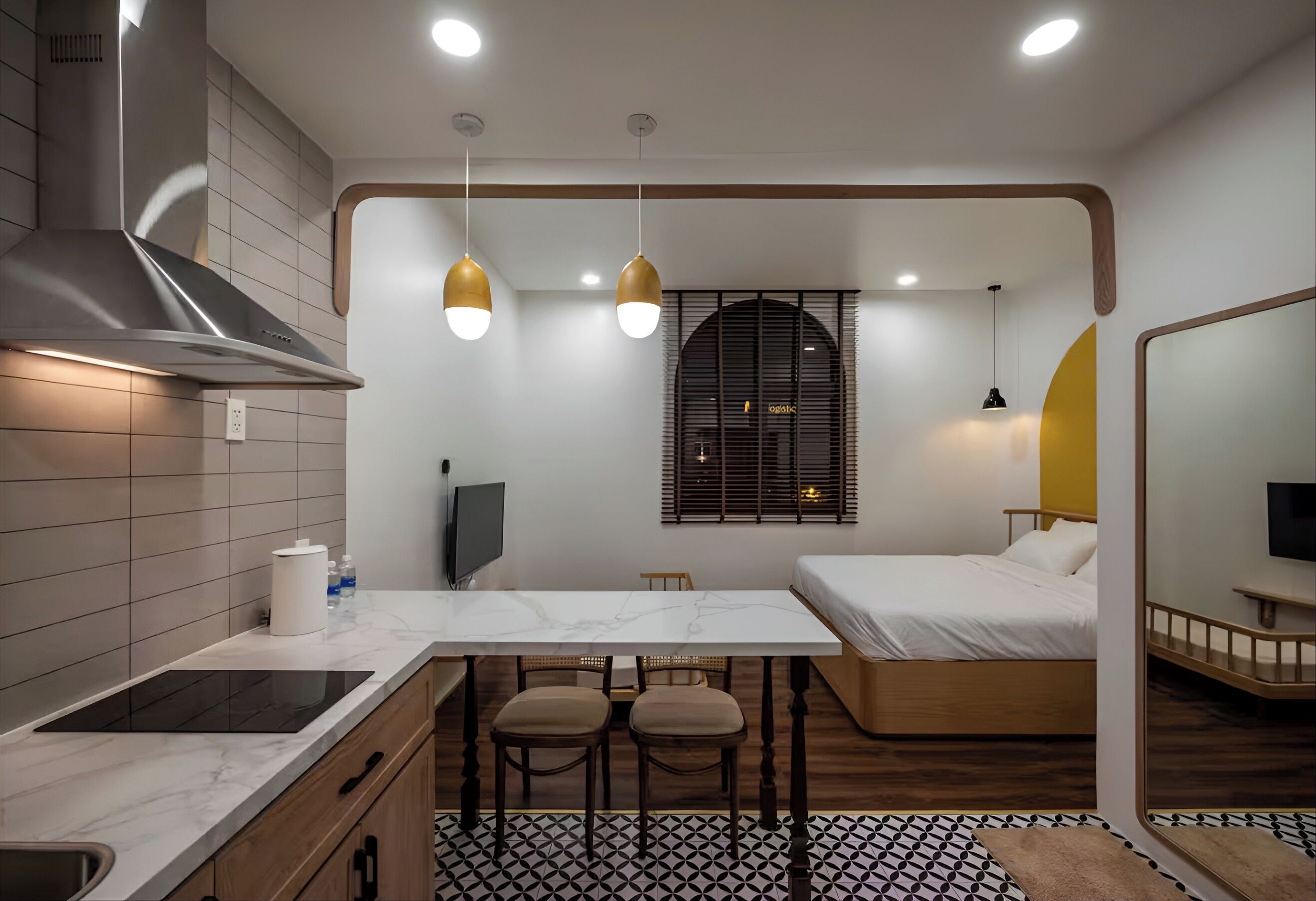 Een compacte hotelkamer met een kitchenette, een bed en een kleine eethoek.