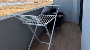 A balcony with a metal drying rack, a small table, and a chair. - Joli Beach House - Charming Second Floor T1 Center - With Balcony (Sal)