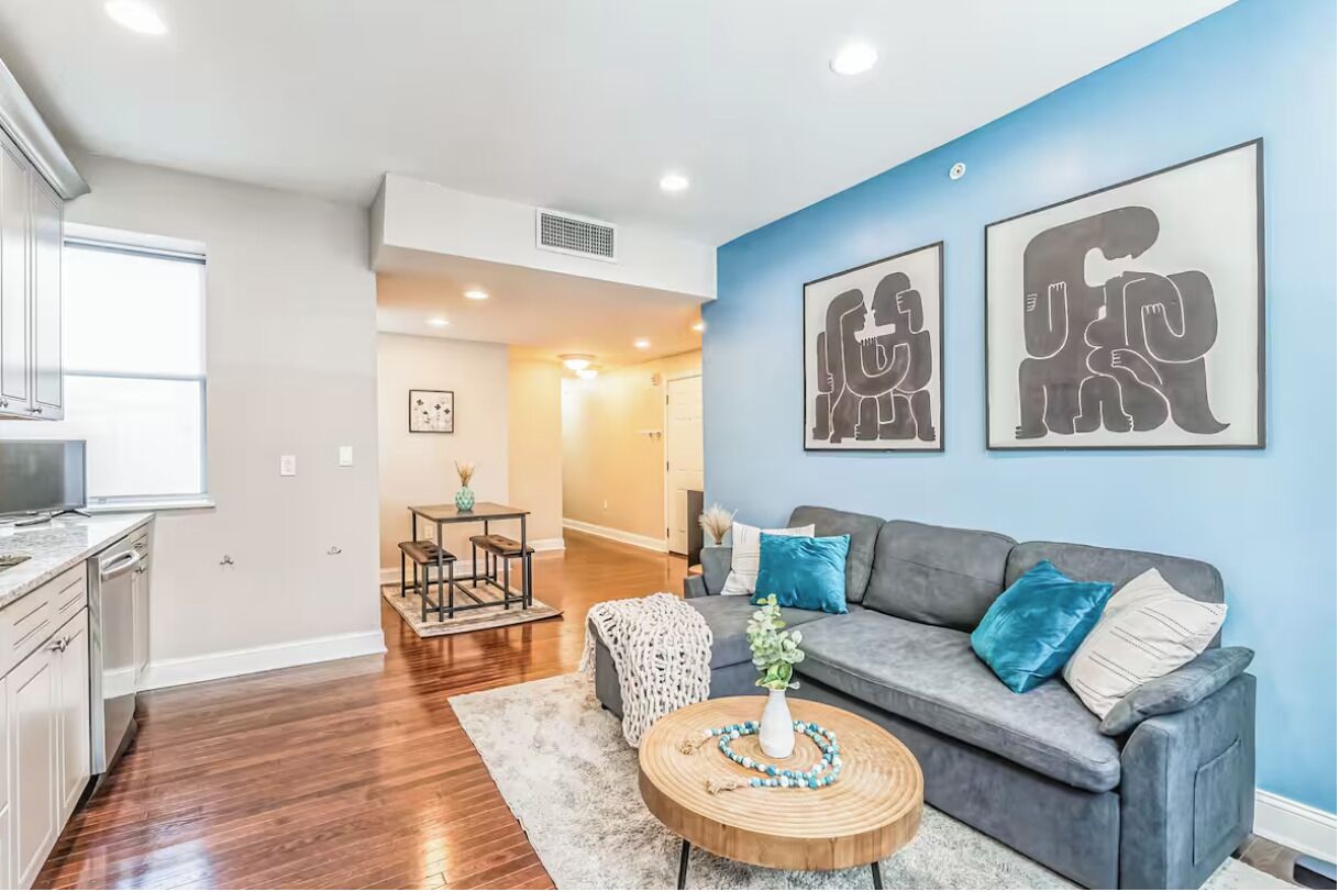 A modern living room with a grey sofa, a round coffee table, and artwork on the wall.