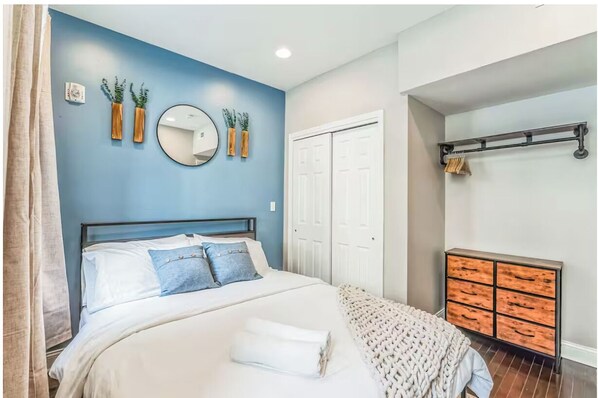 Un dormitorio con cama, cómoda, espejo y puerta.