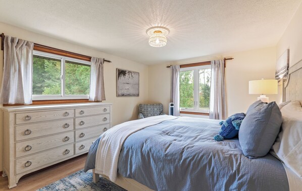 A bedroom with a bed, dresser, windows, and a ceiling light. - Scenic Shores: Your Front Row Seat to Lake Michigan Sunsets (New Era)