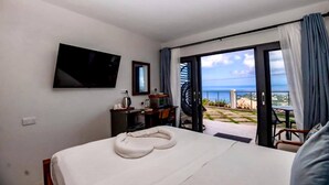 Una habitación de hotel con cama, televisión, escritorio y vista al océano.