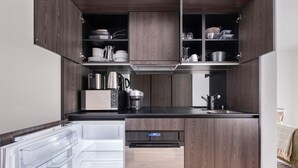 Eine kleine Küche mit Holzausstattung, einer eingebauten Mikrowelle, einer Kaffeemaschine und einem Edelstahlspülbecken.