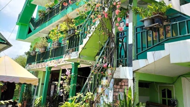 A multi-story building with balconies adorned with potted plants and flowers. - Zackry Guesthouse (Langkawi)