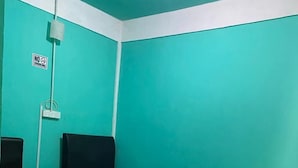 A room with teal walls, a 'No Smoking' sign, two single beds with pillows, a small table, and a patterned floor. - Zackry Guesthouse (Langkawi)