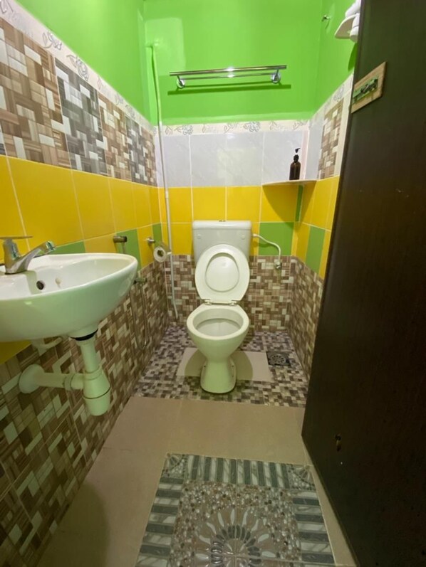 A bathroom with a toilet, sink, and patterned tiles. - Zackry Guesthouse (Langkawi)