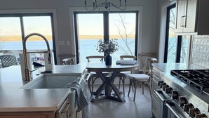 A modern kitchen with a large island, stainless steel appliances, and a view of the water.