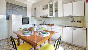 Una cocina con armarios blancos, una mesa de comedor de madera, sillas y un respuesto de azulejos.