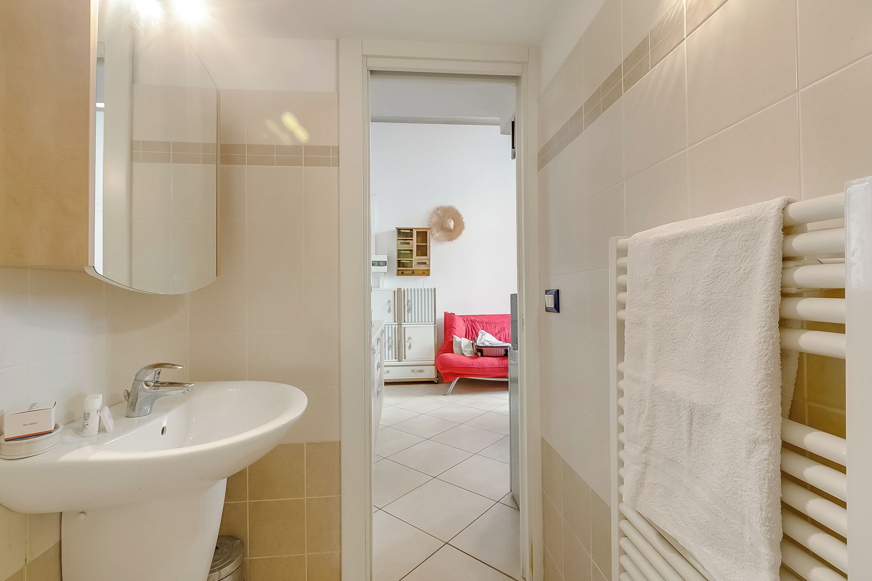 Une salle de bain avec un lavabo blanc, un miroir et un porte-serviettes.