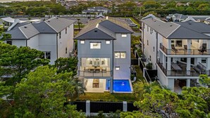 A multi-story residential building with a central courtyard, a swimming pool, and a view of the surrounding neighborhood. - Villa Rosa - Coastal Home Complete with Private Pool and Outdoor Dining (Santa Rosa Beach)