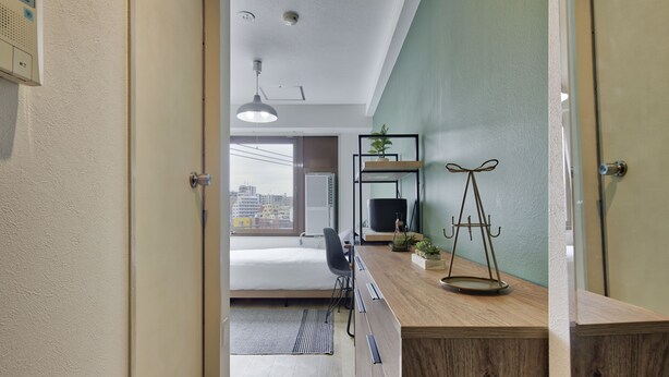 Ein modernes Hotelzimmer mit einem Holzbüro, einem schwarzen Stuhl, einem Bett und Blick auf die Stadt durch das Fenster.
