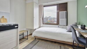 Ein modernes Schlafzimmer mit Bett, Schreibtisch und Fenster mit Blick auf die Stadt.