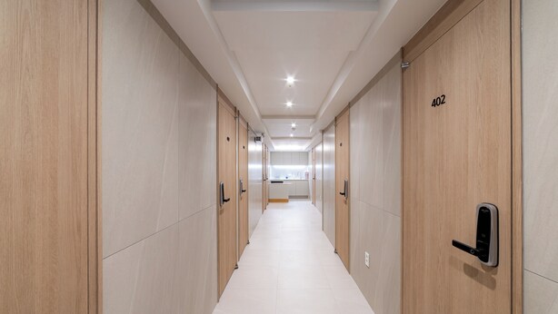 A hallway with wooden doors, numbered 402, leading to a kitchen area. - Hi Dongdaemun Hostel (Seoul)