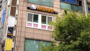 A building with multiple signs, including "Hello" and "Hisada Yum" indicating a hostel. - Hi Dongdaemun Hostel (Seoul)
