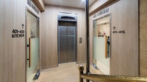 A modern elevator with directional signs for rooms 401-410 and 411-416. - Hi Dongdaemun Hostel (Seoul)
