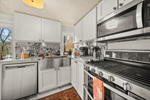A modern kitchen with white cabinets, a stainless steel range, and a built-in microwave.