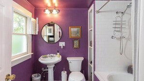 A bathroom with purple walls, a pedestal sink, a toilet, a bathtub, and a shower. - Eureka Springs 3 Bed - Teacup Cottage (Eureka Springs)