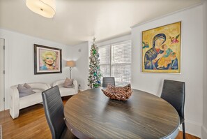 Un coin repas avec une table ronde, des chaises, un sapin de Noël et des œuvres d’art accrochées aux murs.