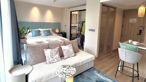 A modern hotel room with a large bed, a sofa, a dining area, and a bathroom visible through an open door. - 1BR 5Min Walk to BeachPool&Gym C243 (Choeng Thale)