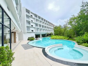 A modern hotel with a large pool area, multiple balconies, and lush greenery. - 1BR 5Min Walk to BeachPool&Gym C243 (Choeng Thale)