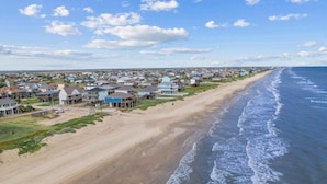 A coastal residential area with houses along the beach, a sandy shoreline, and a clear view of the ocean. - 2nd Row Walk to Beach | Sleeps 22 | Tiki Bar (Crystal Beach)