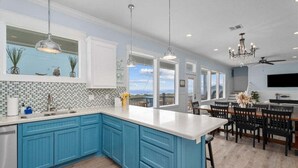 A kitchen with blue cabinets, a white countertop, and a view of the ocean. - 2nd Row Walk to Beach | Sleeps 22 | Tiki Bar (Crystal Beach)
