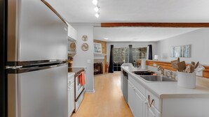 A modern kitchen with white cabinetry, a stainless steel refrigerator, and a wooden floor. - Lake Martin Condo-charming near Auburn-Dadeville in Stillwater (Dadeville)