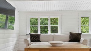 Une pièce avec une table en bois, des murs blancs et un canapé blanc agrémenté de deux coussins.