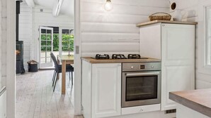 Une cuisine équipée d’une cuisinière, d’un four et d’un luminaire suspendu.