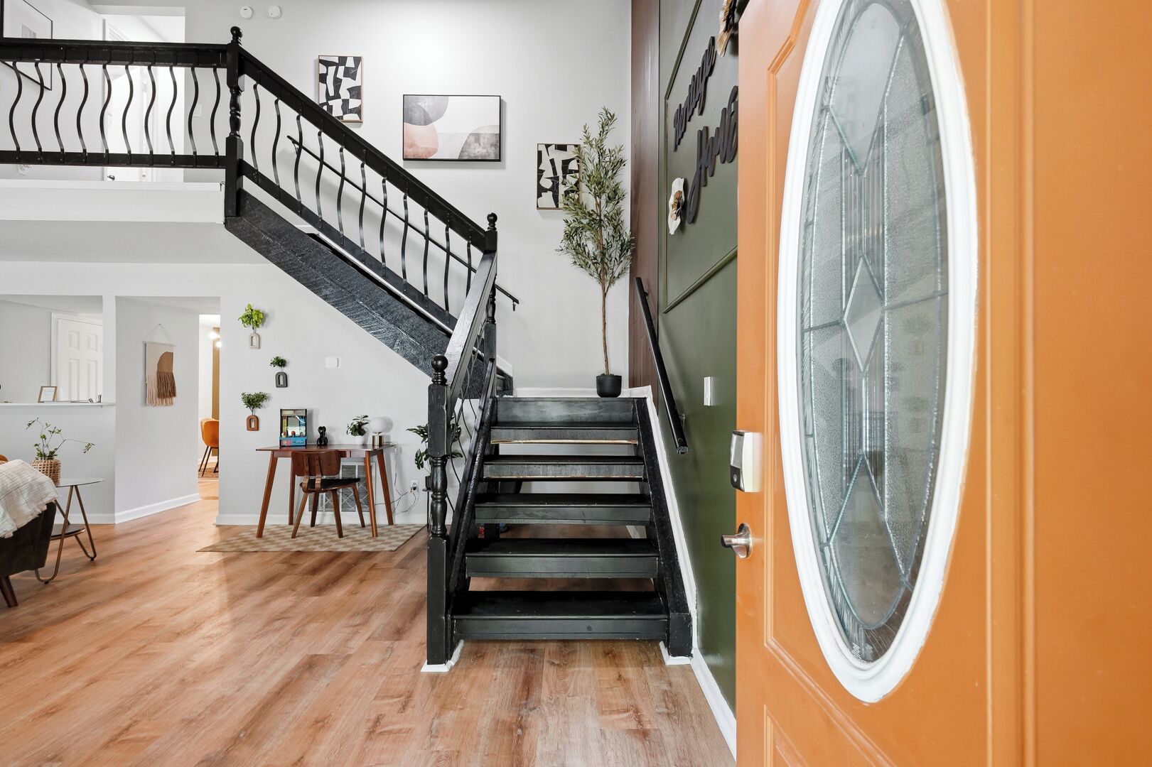 Una escalera con barandal negro que lleva a una habitación con un ventanal grande.