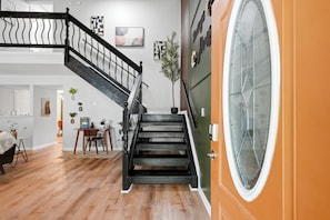 Un escalier avec une rampe noire menant à une pièce dotée d’une grande fenêtre.