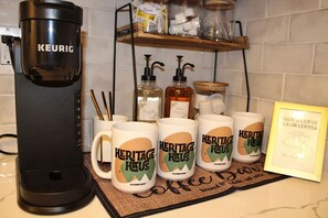 Une machine à café, des tasses et un panneau encadré dans une cuisine.