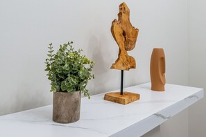 A white marble shelf with a potted plant, a wooden sculpture, and a brown vase. - Heritage Haus: Stylish 2BR Near Marietta Square / Dogs Ok / Parking + WFH Ready (Marietta)