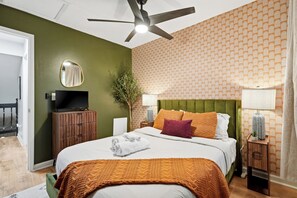 Een hotelkamer met een bed, een televisie, een groen hoofdeinde en een behang met patroon.