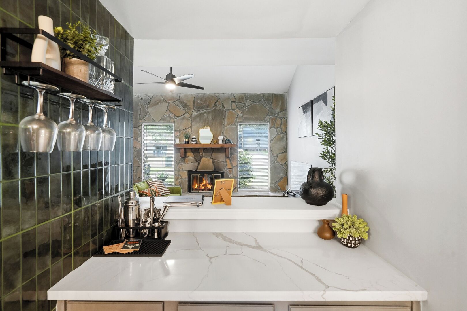 Una cocina moderna con una pared de acento de piedra, una encimera de mármol blanco y una chimenea integrada.