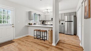 Eine moderne Küche mit weißen Schränken, Edelstahlgeräten und Holzboden.