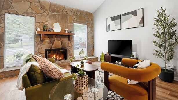 Ein Wohnzimmer mit Kamin aus Stein, einem Flachbildfernseher, einer Couch und einem Couchtisch.