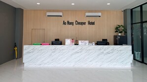 Mostrador de recepción de hotel con encimera de mármol, unidades de aire acondicionado y un letrero que dice 'Ao Nang Cheaper Hotel'.