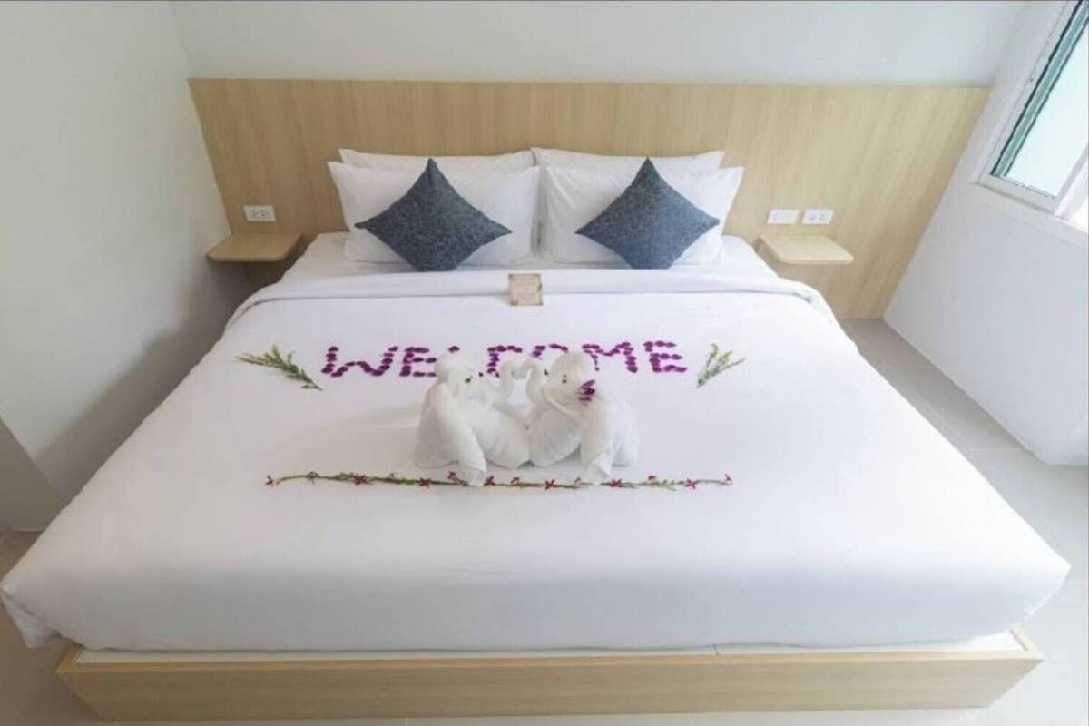Un letto con un cartello che dice 'WELCOME', due cuscini e un oggetto decorativo a forma d'orso.