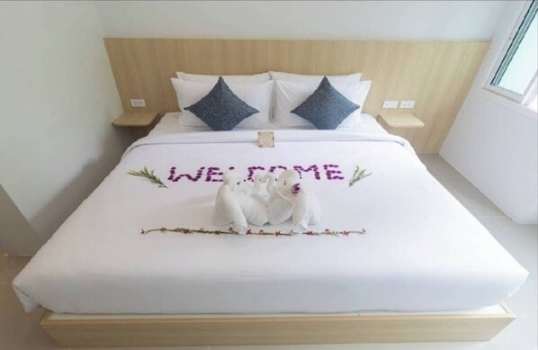A bed with a 'WELCOME' sign, two pillows, and a decorative item resembling a bear. - Ao Nang Cheaper Hotel (Krabi)