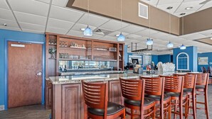 A bar area with wooden bar stools and a counter displaying glasses and bottles.