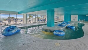 An indoor swimming pool with blue water slides and lounge chairs.
