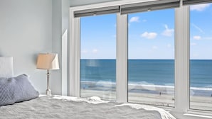 A bedroom with a large window overlooking a beach. - Panoramic Ocean View Condo with Pool (North Myrtle Beach)