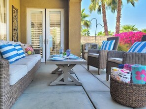 Eine Terrassenfläche mit Korbmöbeln, einem Tisch gedeckt mit Tellern und Gläsern, und einem Korb mit Babyausstattung.
