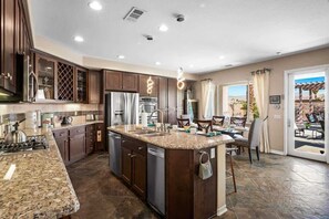 A kitchen with granite countertops, dark cabinetry, and a central island.