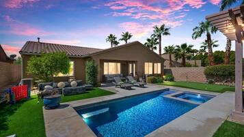 Propiedad residencial con piscina, mobiliario de patio y zona de estar exterior cubierta.